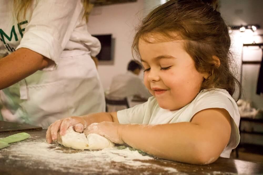 Girl rolling dough on a family friendly pizza & tiramisu making class in Rome