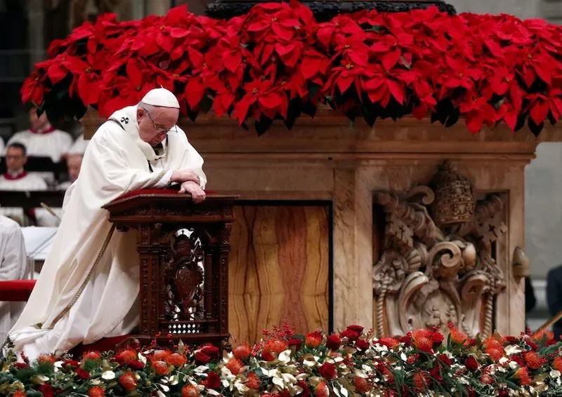 Pope Francis presiding over Christmas Midnight Mass in St. Peter's Basilica, Vatican City, with poinsettia decorations