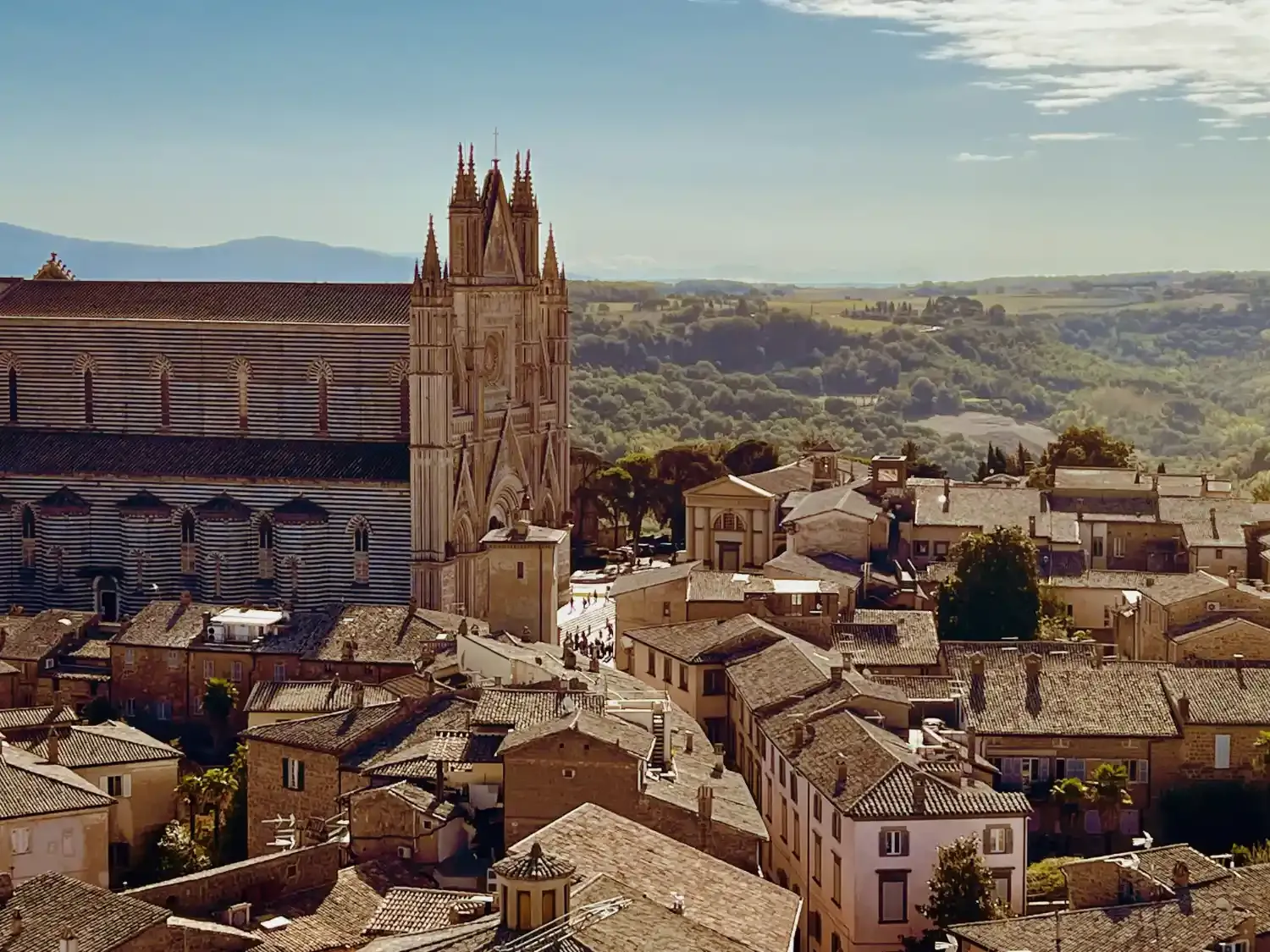 Orvieto Cathedral with bell tower overlooking historic city rooftops and Umbrian countryside landscape